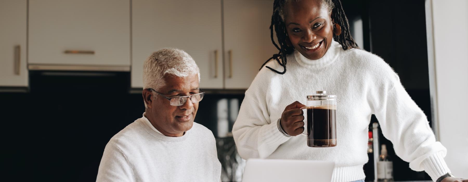 a man and a woman sitting at a table with a laptop and a coffee mug